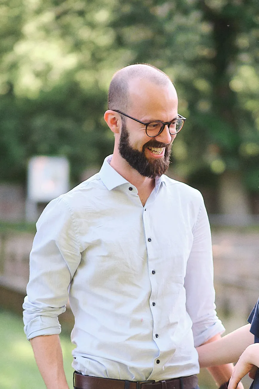 Ein helles freundliches Bild von einem Mann mit kurzem Haar, Brille und vollem Bart lacht glücklich übers ganze Gesicht.